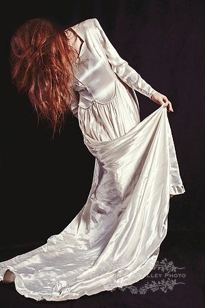 A young Woman Wearing an Old Fashioned Dress with Hair Covering Her Face