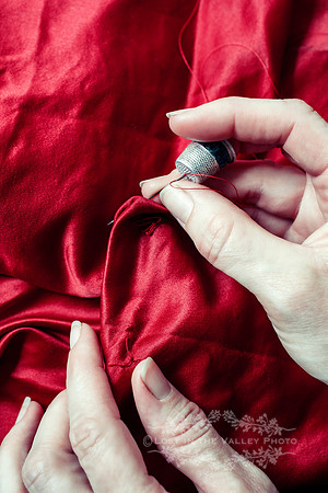 Hands of a Woman Sewing Red Silk