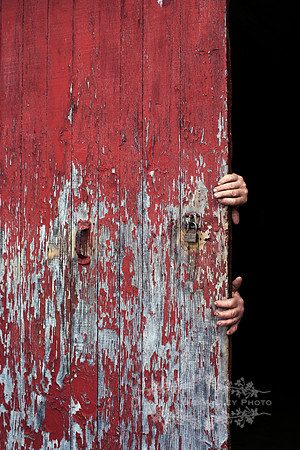 Man's Hands Holding a Weathered Red Door